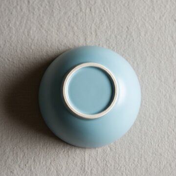 Minimalist blue ceramic bowl underside view on textured grey background