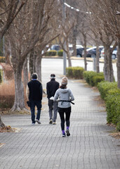 冬の公園でジョギングするシニア男性とランニングする女性の姿