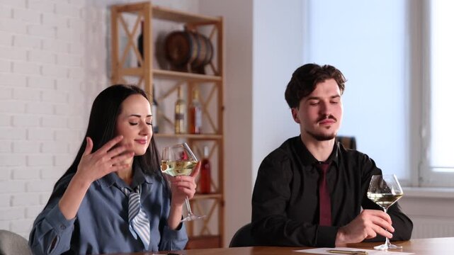 Professional sommeliers with glasses of white wine filling out tasting card at table indoors