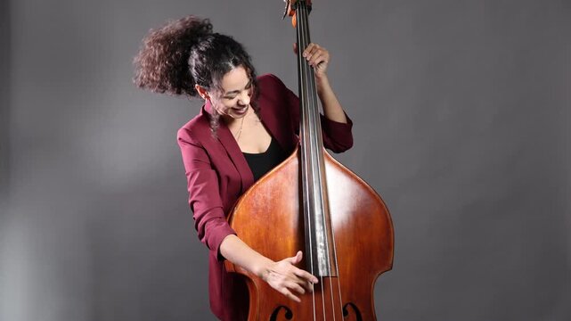Woman playing double bass on grey background