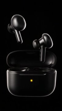 Pair of Modern Black Wireless Earbuds Hovering Above Charging Case on Isolated Black Background