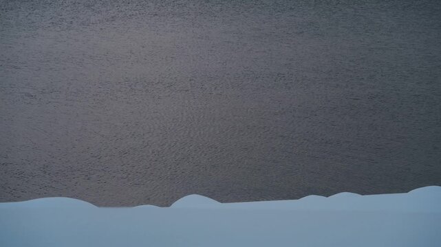 鈍く光る水面と湖畔の雪景色