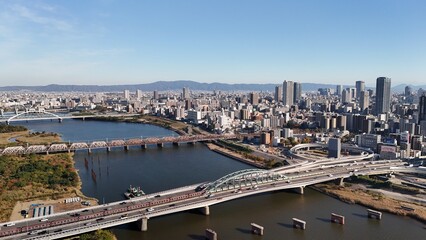 Obraz premium Osaka City, Japan: Aerial Drone View of CBD, Skyscrapers, Urban Cityscape, Yodogawa Riverside Park, Yodo River, Osaka Skylines, Shin-Yodogawa Bridge, Railway Bridges in Yodogawa Ward, Kita Ward
