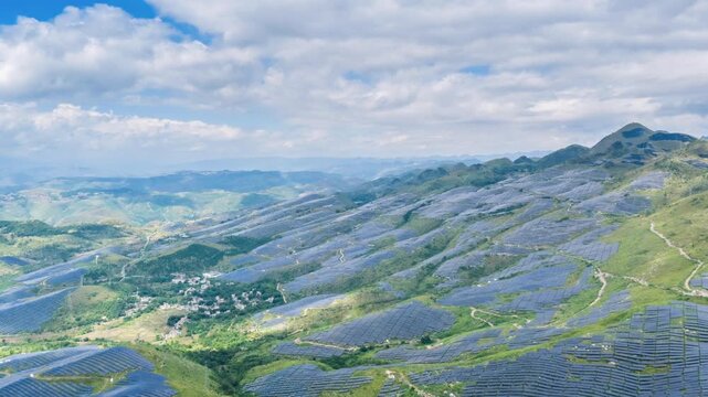Aerial time-lapse of a large solar farm in rocky desertification mountains, with photovoltaic panels covering rolling hills, clean energy meets ecological restoration.