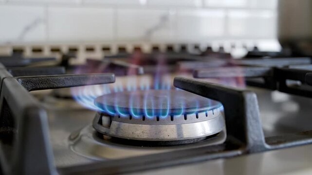 Close up of a gas stovetop burner with a blue flame on