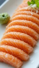 Fresh salmon sashimi slices arranged neatly on a plate with wasabi, shredded radish, and parsley garnish in background