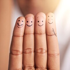 Four fingers closely aligned, each with a smiley face drawn on them, against a blurred, creamy background