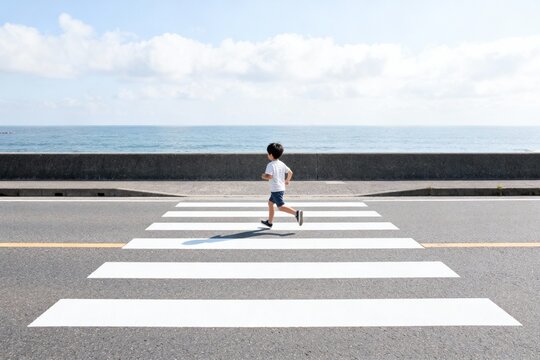 Child running on zebra crossing by sea