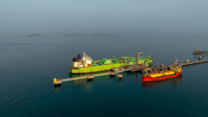 Fototapeta premium Aerial view LPG tanker ship at oil and gas terminal platform, Liquefied Petroleum Gas tanker ship industrial oil gas terminal tanker ship, LPG tanker ship loading and unloading petrochemical industry.