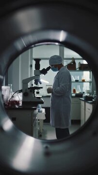 Researcher in Lab Coat Conducting Experiments with Microscope in Modern Laboratory Setting