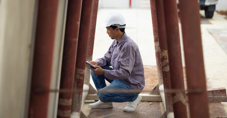 japanese Professional Architects Engineer working at construction site. Asian Man Architect or contractor working on house building under construction site. Civil Engineering in safety harthat helmet
