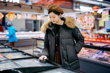 Fototapeta premium Woman Shopping in Supermarket Freezer Section