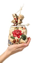 Hand holding a patterned fabric pouch, accented with a metal clasp and knotted string closure, isolated on white