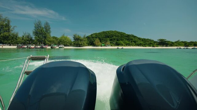 Speedboat departing Pig Island with twin outboard engines, turquoise tropical sea and green island shoreline during excursion trip
