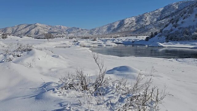 A frozen lake stretches across a snowy plain beneath clear blue skies, surrounded by untouched mountains and sparse winter vegetation.
📍Marivan, Kurdistan 