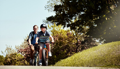 Cycling, summer and dad with child on bicycle for bonding, exercise and learning together outdoor. Family, neighborhood and father with boy on bike ride for connection, support and hobby on weekend