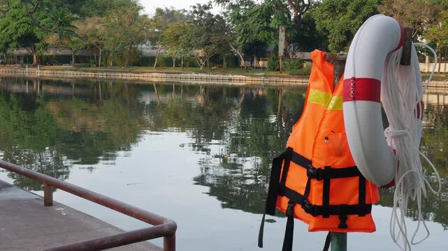 Life Jacket and Buoy: Orange Safety Vest Floating Device Water Rescue Equipment Pool Reflection Background