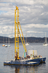 Outdoor view of a floating pile driving rig moored just offshore