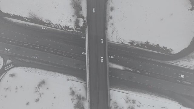 4K 60fps aerial static top view of a highway cloverleaf interchange in winter fog, cinematic grainy atmosphere.