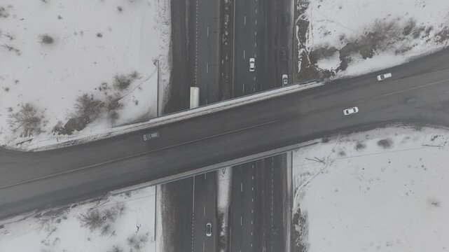 4K 60fps aerial static top view of a highway cloverleaf interchange in winter fog, cinematic grainy atmosphere.