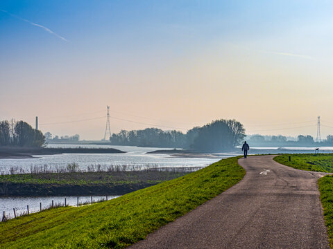 Person walking along Waalbandijk levee by Waal river