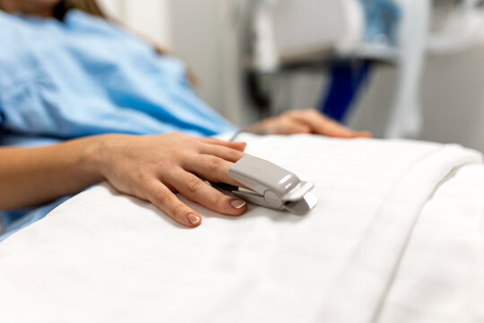 Close up of Patient Hand with Pulse Oximeter Finger Sensor. Pulse Ox Monitoring Vital Signs in Hospital Bed. Healthcare and Medicine Concept. Medical Equipment Measuring Heart Rate and Oxygen.