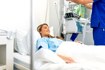 Patient in hospital bed. Female patient smiling in clinic, healthcare and medicine concept. Young woman lying in a medical ward while doctor or male nurse works with equipment in the background.