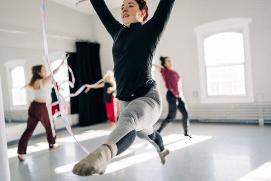 Gymnast performing rhythmic ribbon routine in bright studio