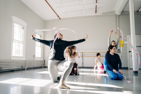 Women practicing rhythmic gymnastics with ribbons in studio