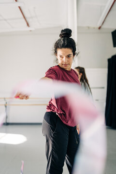 Focused dancer extends ribbon in mid-movement at studio