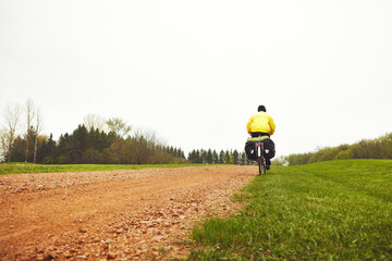 Obraz premium Outdoor, cyclist and travel with bicycle, winter or adventure with raincoat, back or journey on bike. Space, cycling and person with eco friendly transport for trip, holiday and riding in nature