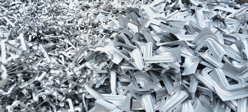 Pile of shiny aluminum scrap metal parts for recycling in industrial yard