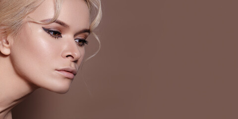 Obraz premium High Glam White Model Dewy Skin Rendered With Luminous Highlight, Sharp Eyeliner Wing, Sculpted Cheekbones, Flawless Finish, Neutral Brown Backdrop, Beauty Editorial Mood, Influencer Ready Look