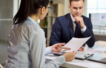 Fototapeta premium Analyst woman presenting report to colleague in office. They review numbers at laptop during meeting discussion and plan budgets for finance. Concept of presentation planning and teamwork.