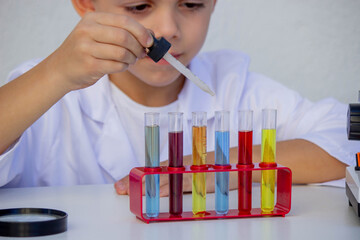 Little boy adding reagent into a test tube during a chemistry experiment