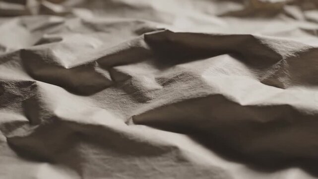 Cinematic slow motion movement of an animated crinkled paper texture background with organic creased parchment folds in a seamless looping video sequence for artistic creative design projects.