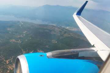 Fototapeta premium High angle view from an airplane window showing the wing and engine over a mountain landscape.