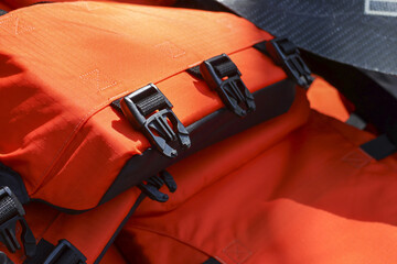Close up of an orange life jacket with black buckle and strap. This safety equipment for water...