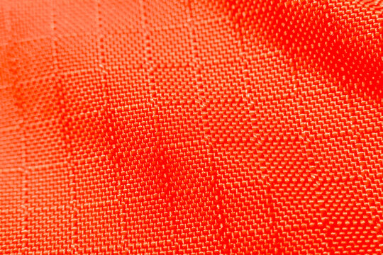 Vibrant orange fabric texture with woven synthetic material pattern. An abstract close up of grid background showing durable textile detail for modern design