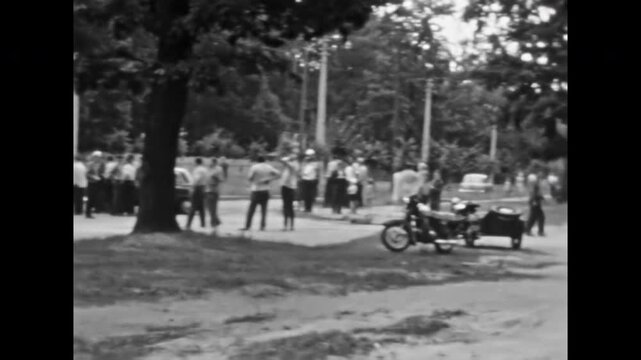 Crowd of people gathered around incident, traffic accident. Onlookers on street after motorcycle collision, police officer arriving on sidecar. Old film. Archival retro 1960s. Vintage archive.