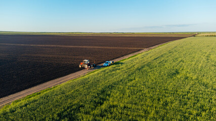 Obraz premium A tractor in a field with a seeder in spring, aerial view