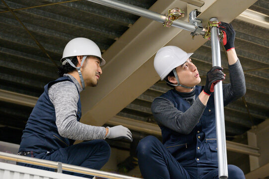天井裏で工事をする日本人男性
