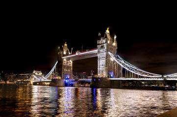 Obraz premium Tower Bridge at Night in London: Iconic Illuminated Suspension Bridge Over the River Thames with City Lights Reflection