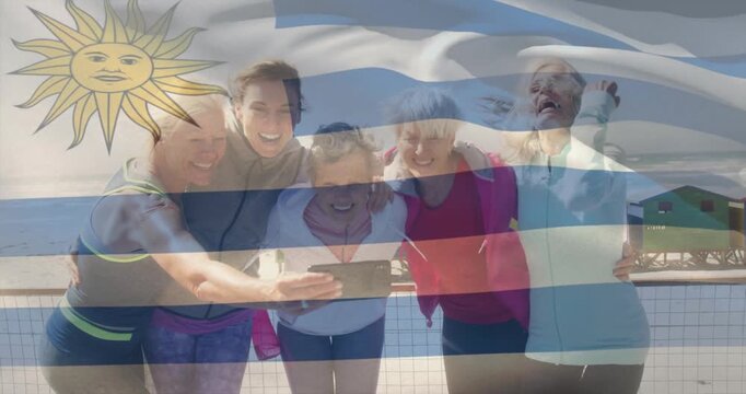 Taking selfie, group of women smiling with Uruguay flag in background