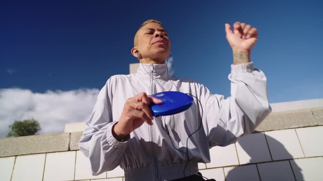 Androgynous person dancing and listening to music on a portable cd player