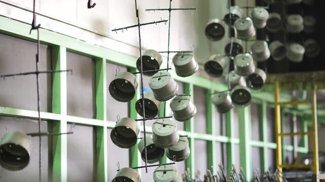 Industrial workshop with metal parts suspended for painting in manufacturing facility