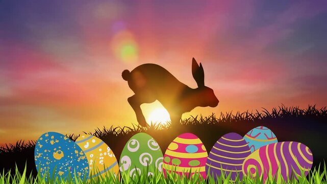 Silhouette of a rabbit jumping over colorful Easter eggs at sunset.