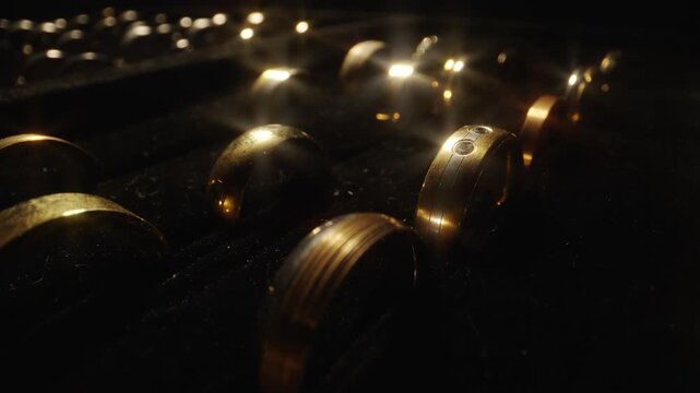Camera sliding over rows of luxury gold wedding rings in a display box.