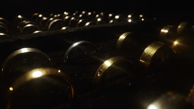 Camera sliding over rows of luxury gold wedding rings in a display box.
