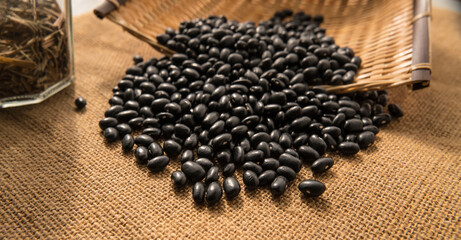 Background image. Black beans scattered in a straw container.
